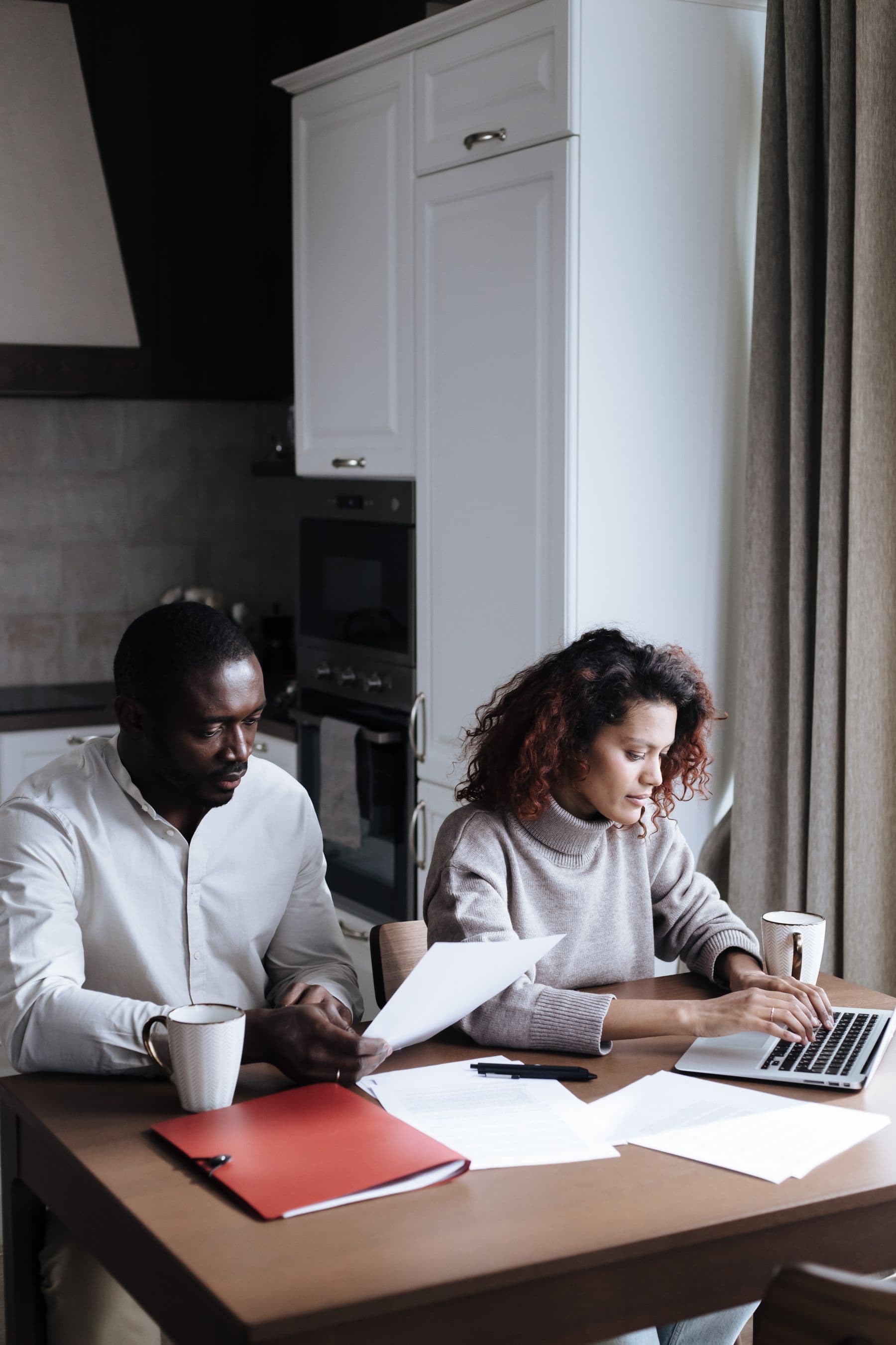 A couple reviewing household documents together at a kitchen table