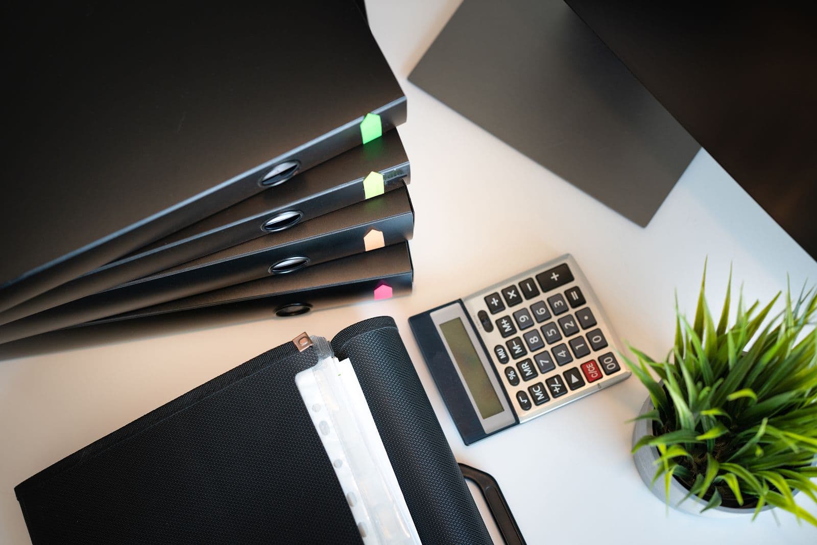 An organized desk with document folders, a calculator, and a plant